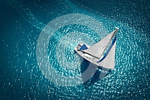 Regatta sailing ship yachts with white sails at opened sea. Aerial view of sailboat in windy condition