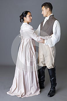 A Regency couple in a romantic embrace against a grey backdrop