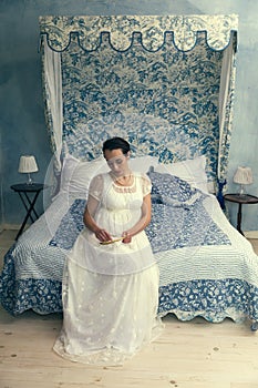 Regency lady sitting on canopy bed photo