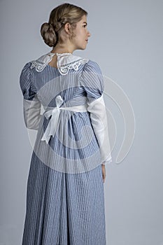 Regency woman in blue striped dress on plain background