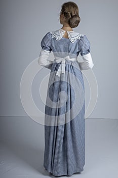 Regency woman in blue striped dress on plain background