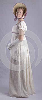 Regency woman in cream dress and bonnet on studio backdrop