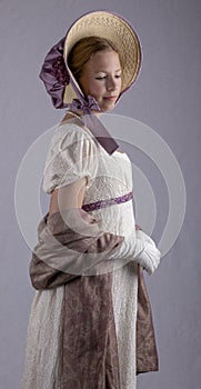 Regency woman in cream dress and bonnet on studio backdrop
