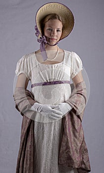 Regency woman in cream dress and bonnet on studio backdrop