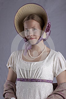 Regency woman in cream dress and bonnet on studio backdrop