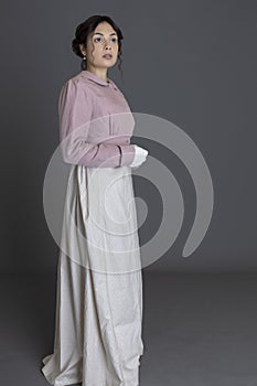 A Regency woman wearing a printed cotton dress and a pink linen short spencer and a pink linen short spencer