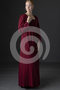 A Regency woman wearing a  red linen dress against a studio backdrop