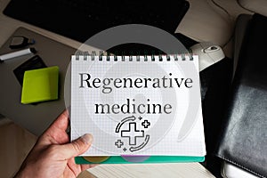 Regenerative medicine word on notebook holding man against desktop photo