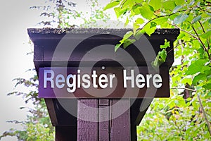 A register here information sign on a post