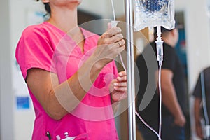 Registered nurse wearing hot pink scrubs hangs IV photo