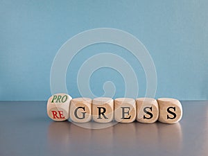 Regress or progress symbol. Turned wooden cubes and changes the word Regress to Progress.