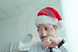 Regretful businessman with Santa Claus hat suffering from Christmas holiday season depression