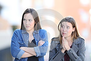 Regretful girl asking forgiveness to her angry friend photo