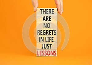 Regrets or lessons symbol. Concept words There are no regrets in life just lessons on wooden blocks on a beautiful orange