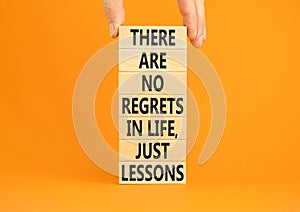 Regrets or lessons symbol. Concept words There are no regrets in life just lessons on wooden blocks on a beautiful orange