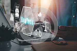 Person working on laptop computer with RegTech icon on virtual screen