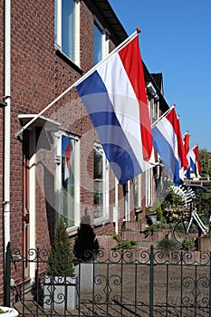 Regular Dutch street houses waving national flag and orange streamer. Koningsdag Kingsday and Bevrijdingsdag Liberation Day,