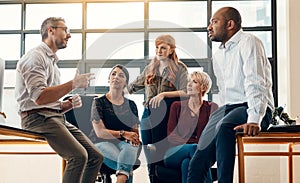 Regular meetings keep their team close. a group of businesspeople having a discussion in a modern office.