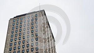 Regular rectangular windows on block of flats / offices building. Overcast sky background