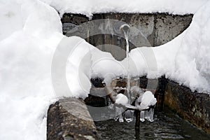 Regulated natural spring or source of water arranged into a fountain in winter captured in front view.