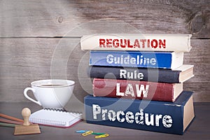 Regulation concept. Stack of books on wooden desk photo