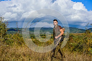 Regulation of hunting. Man muscular brutal guy gamekeeper nature background. Hunter rifle gun stand top of mountain. Guy photo