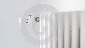 Regulator knob on white heating radiator in room