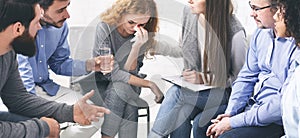 Rehab community members supporting crying emotional woman at group therapy session