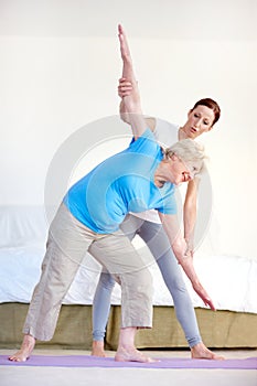 Rehabilitating exercises - Senior Health. Full-length of an elderly woman doing stretches with her fitness trainer.