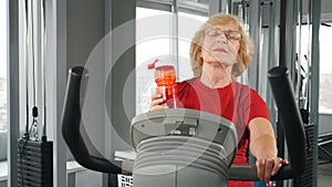 Rehabilitation centre gym, recovery from injuries and fractures. Elderly woman performing exercise on simulator. Healthy