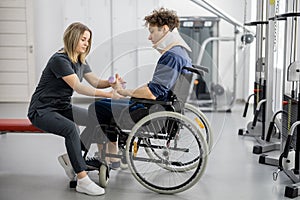 Rehabilitation specialist with guy on a wheelchair doing exercise