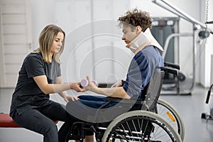 Rehabilitation specialist with guy on a wheelchair doing exercise