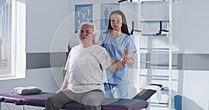 Rehabilitation therapist stretching arm of elderly man