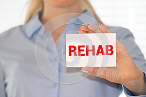 REHABILITATION word on the card shown by a man