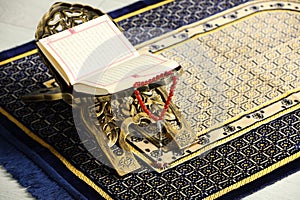 Rehal with open Quran and Misbaha on Muslim prayer rug