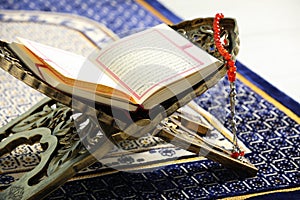 Rehal with open Quran and Misbaha on Muslim prayer rug, closeup