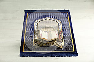 Rehal with open Quran and Misbaha on Muslim prayer rug indoors