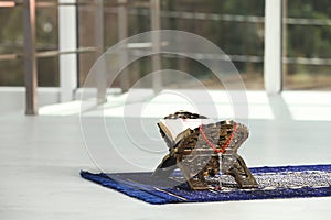 Rehal with open Quran and Misbaha on Muslim prayer rug near window indoors, space for text