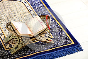 Rehal with open Quran and Misbaha on Muslim prayer rug, space for text