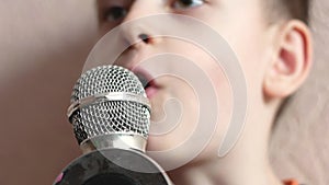 Rehearsal in the children`s vocal studio. Close up portrait of Caucasian boy 6-8 years old singing into microphone. Teaching a chi