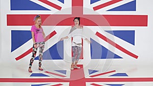 Rehearsal of two beautiful girls actively dancing on background of british flag