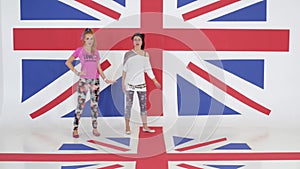 Rehearsal of two charming girls dancing on background of british flag