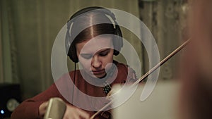 Rehearsing an instrumental melody with violin by female musician with headphones