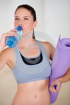 Rehydrating. An attractive young woman drinking a bottle of water.