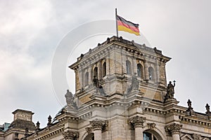 The Reichstag in Berlin with tower and figures and the flag of Germany