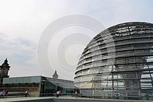 Reichstag dome exterior in summer with yellow sunlight reflection on glass window and clouds in blue sky background