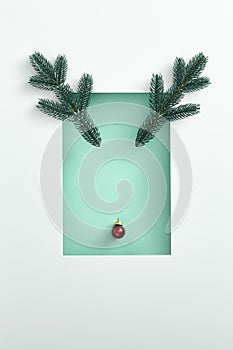 Reindeer face made of red xmas ball and evergreen branch with white border