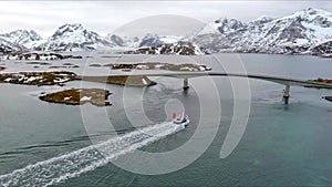 Reine artic bridge with fishing boat, Norway winter aerial 4k video Lofoten Archipelago