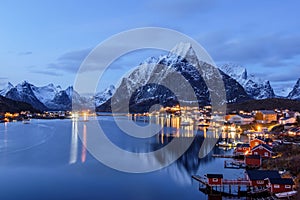 Reine, snow covered mountains in the background and the fishing cabins Rorbu in the foreground, Lofoten Islands, Norway