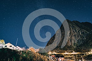 Reinebringen with Milky Way over mountains. Village of Reine Hamnoy Sakrisoy Lofoten islands. Night landscape with road